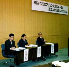 1998(平成10)年11月23日の設立大会・記念シンポジウム。写真は、左から内藤正明代表・稲盛和夫(※)京都商工会議所会頭代理 小堀脩(※)専務理事・桝本頼兼(※)京都市長(※印は当時)。